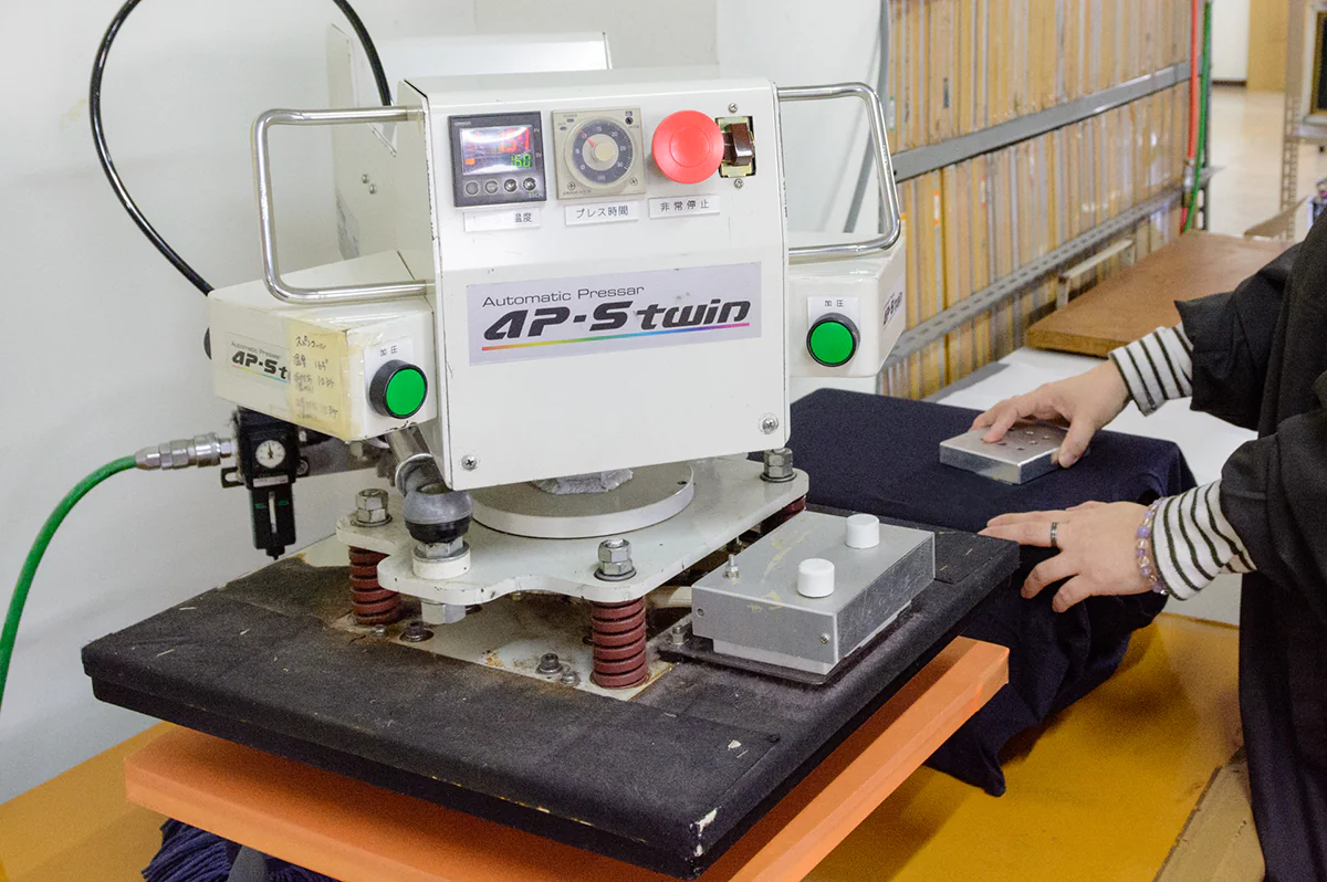 ヒートプレス機で熱と圧力をかけてフィルムを生地に圧着する工程